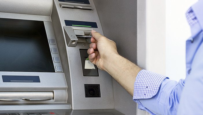 A man inserting a bank card into a cashpoint machine.